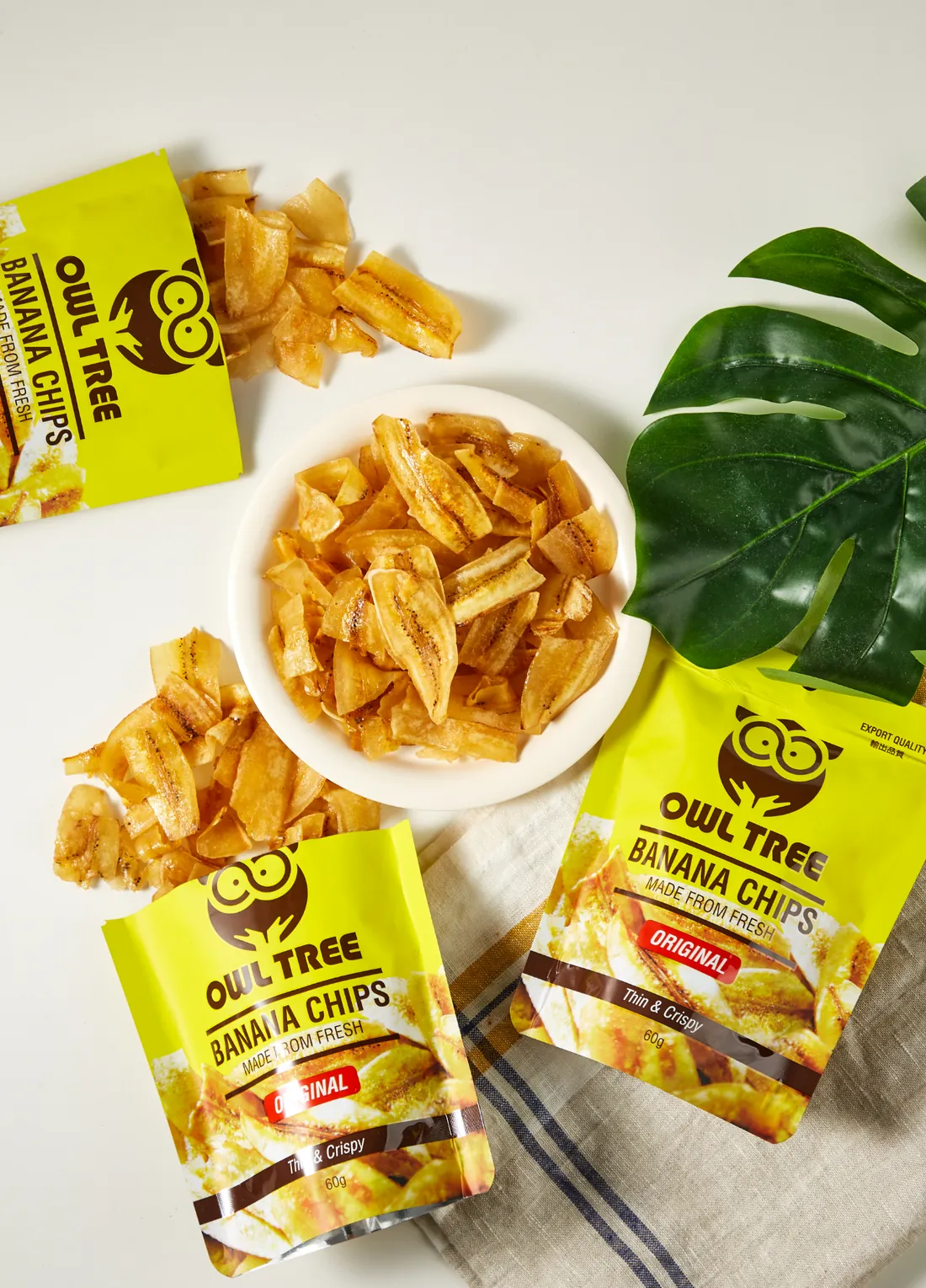 OWLTREE packs with a bowl of banana chips and a palm leaf